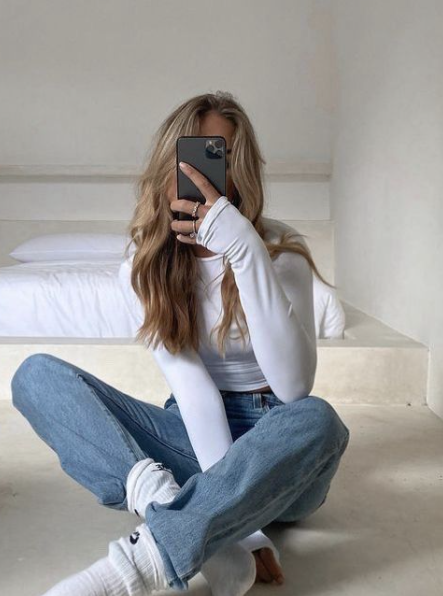 Woman taking a mirror selfie with phone covering her face